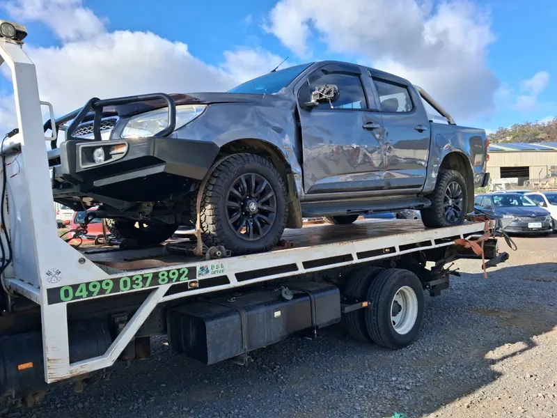 A grey Holden Colorado dual cab with side damage strapped on the tilt tray