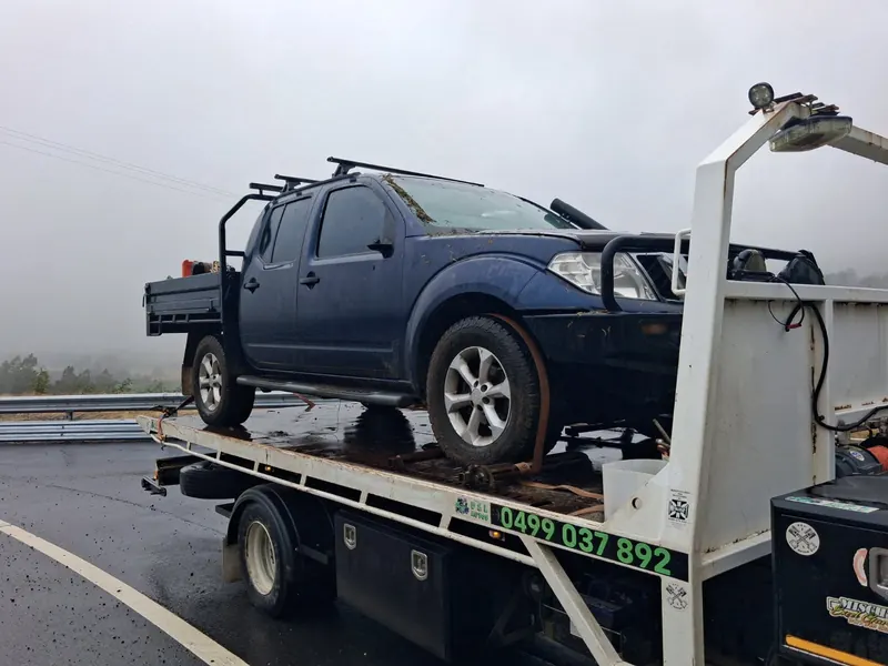 A navy Nissan Navara tray-back on the tilt tray on a wet, foggy highway